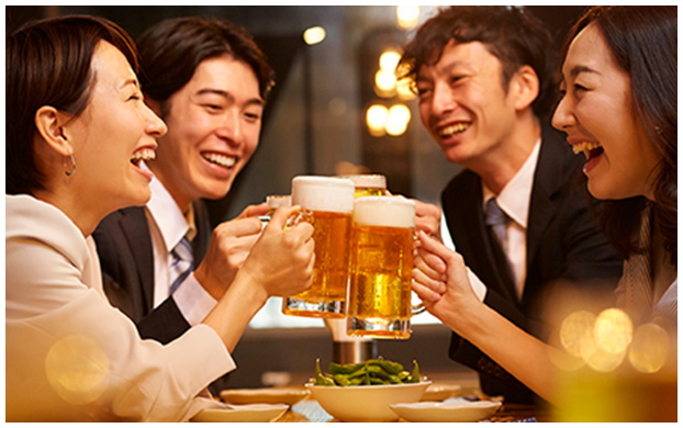 写真：男女4人がビールのジェッキを手に乾杯をしている